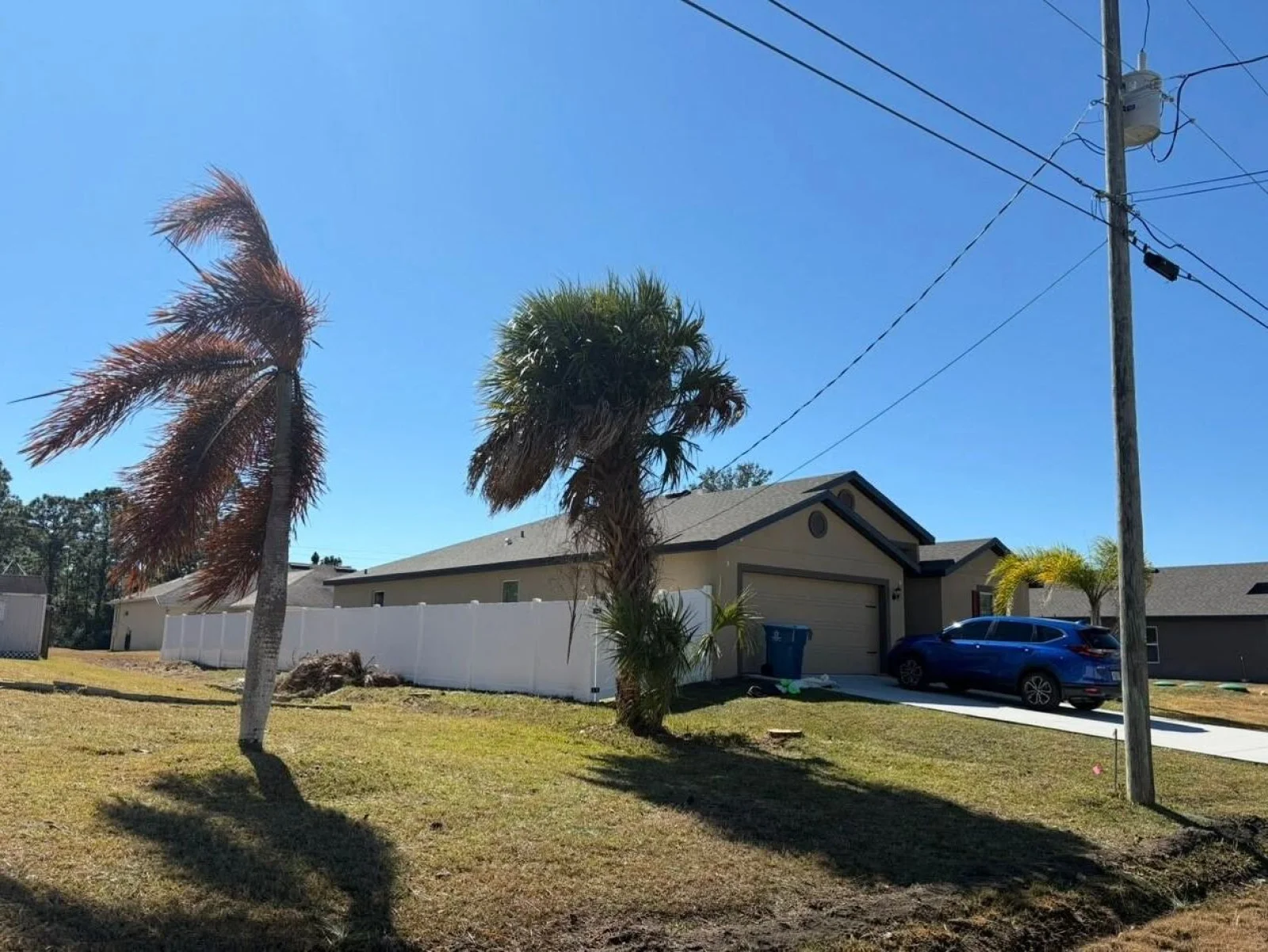 The same yard with the pines gone and open sky above the house.